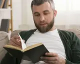 Mężczyzna z brodą czyta książkę, przeglądając strony. Na półce w tle widać **książki chronologicznie**.