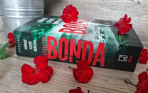Katarzyna Bonda, autorka serii z Huberta Meyerem, na tle czerwonych kwiatów.