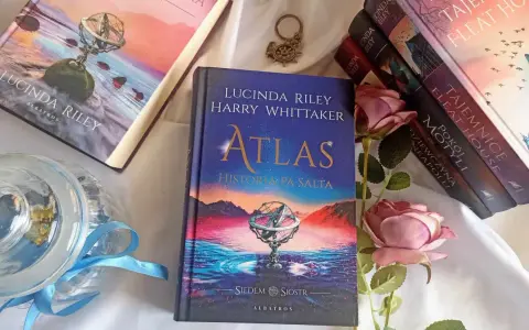 Książka "Atlas. Historia pa Salta" z serii "Siedem sióstr" Lucindy Riley i Harry'ego Whittakera, obok innych tomów cyklu i róż.