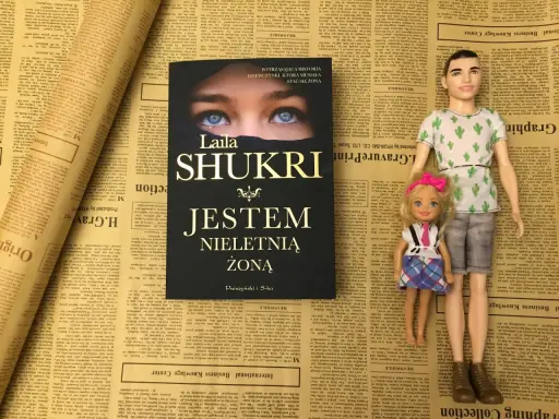 Okładka książki Laila Shukri "Jestem nieletnią żoną" na tle gazet. Obok lalki Ken i Barbie.