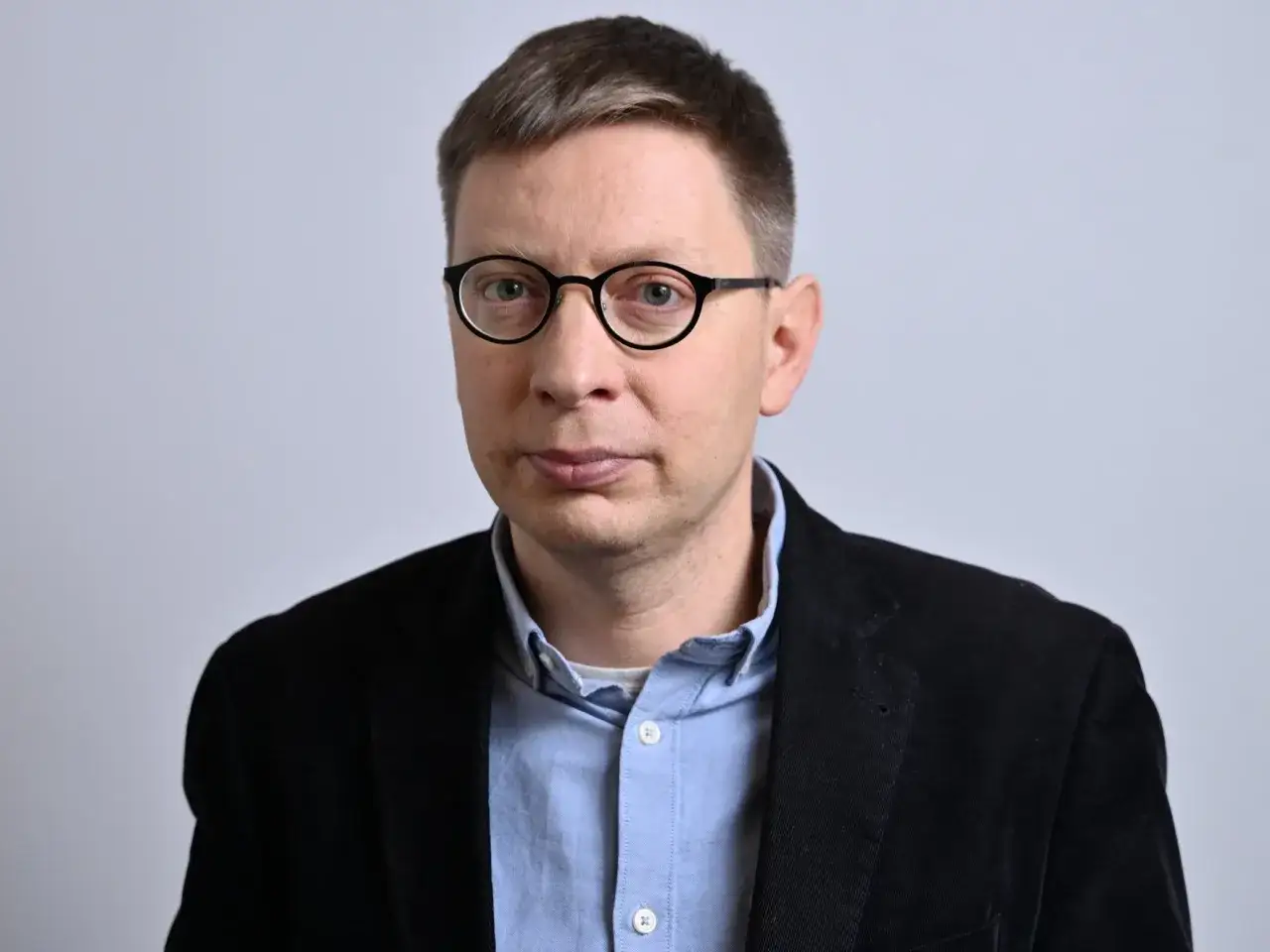 Portret Michała Bilewicza w okularach i czarnej marynarce.